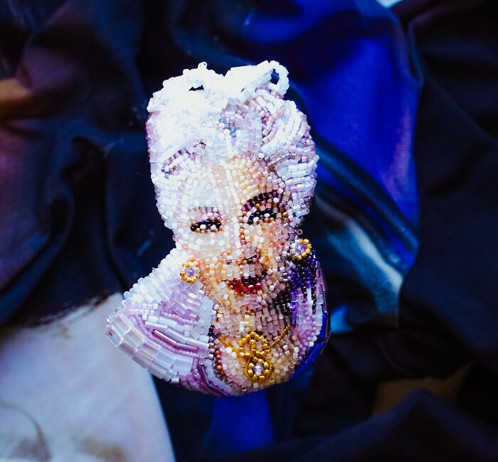 Close-up of a glamorous beaded creation by Tiffany Pisani, a brooch depicting a woman with elaborate hair.