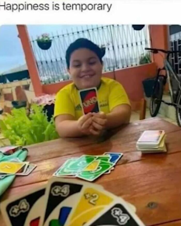 Wholesome posts show a young boy smiling while holding an UNO card during a game with friends.