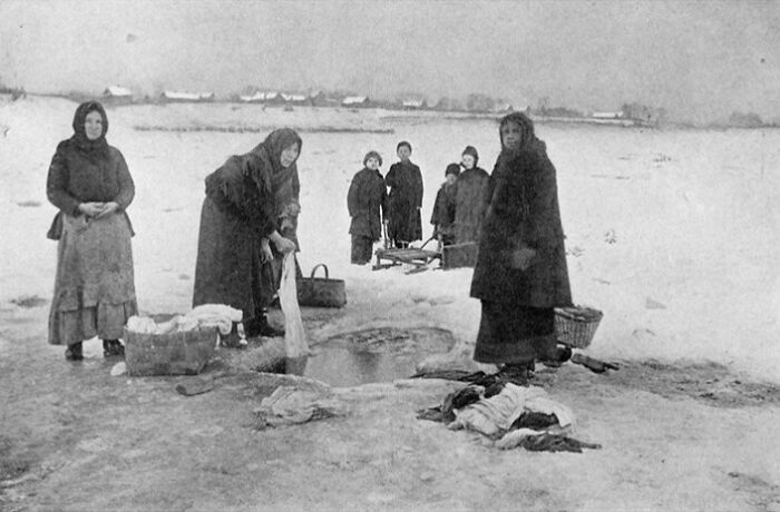 A group of women washing clothes in a frozen river, a historical moment of daily life.