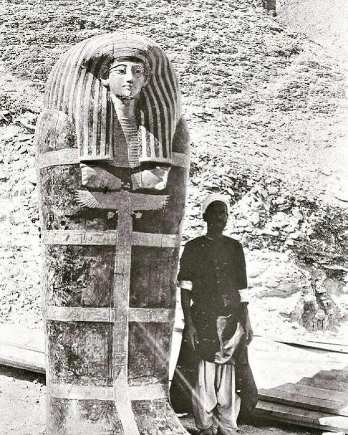 A man standing beside an ancient Egyptian sarcophagus, a significant historical moment nearly lost to history.