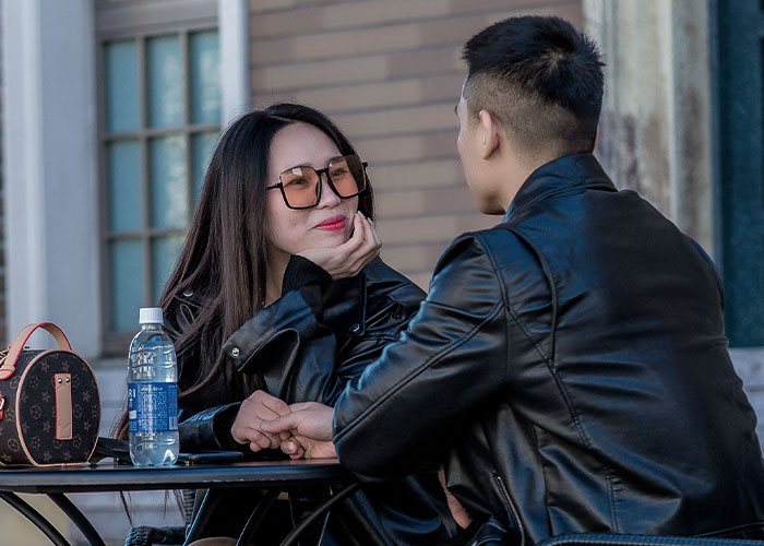 A couple holds hands at an outdoor cafe, a stark contrast to tales of worst first dates with women.