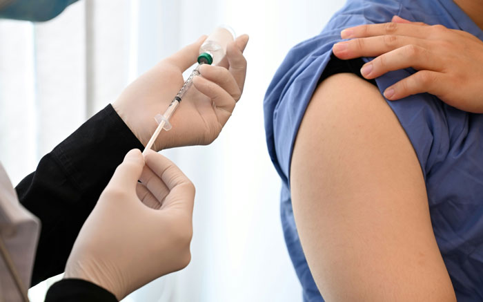 A healthcare professional giving an injection to a patient's arm, signifying a moment of casual conversation about being wife material.