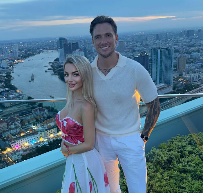 A young woman and man next to your bed, standing on a rooftop overlooking a city, after her nightmare Bali experience.