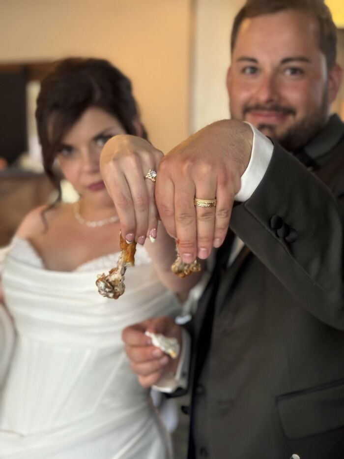 Funny wedding photo of a bride and groom showing off their wedding rings while holding chicken drumsticks.