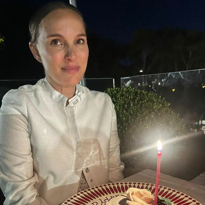 Natalie Portman smiles at a birthday candle, seemingly unfazed by talk of her diva reputation.