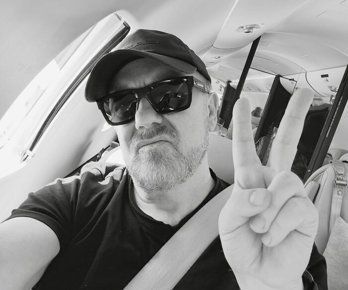 Ricky Gervais in sunglasses and a hat, making a peace sign, discussing marriage plans. Ricky Gervais in sunglasses and a hat, making a peace sign, discussing marriage plans.