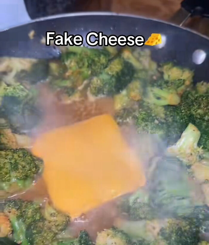 Broccoli in a pan with a melting slice of fake cheese on top, exposing fake foods Americans eat everyday. Broccoli in a pan with a melting slice of fake cheese on top, exposing fake foods Americans eat everyday.