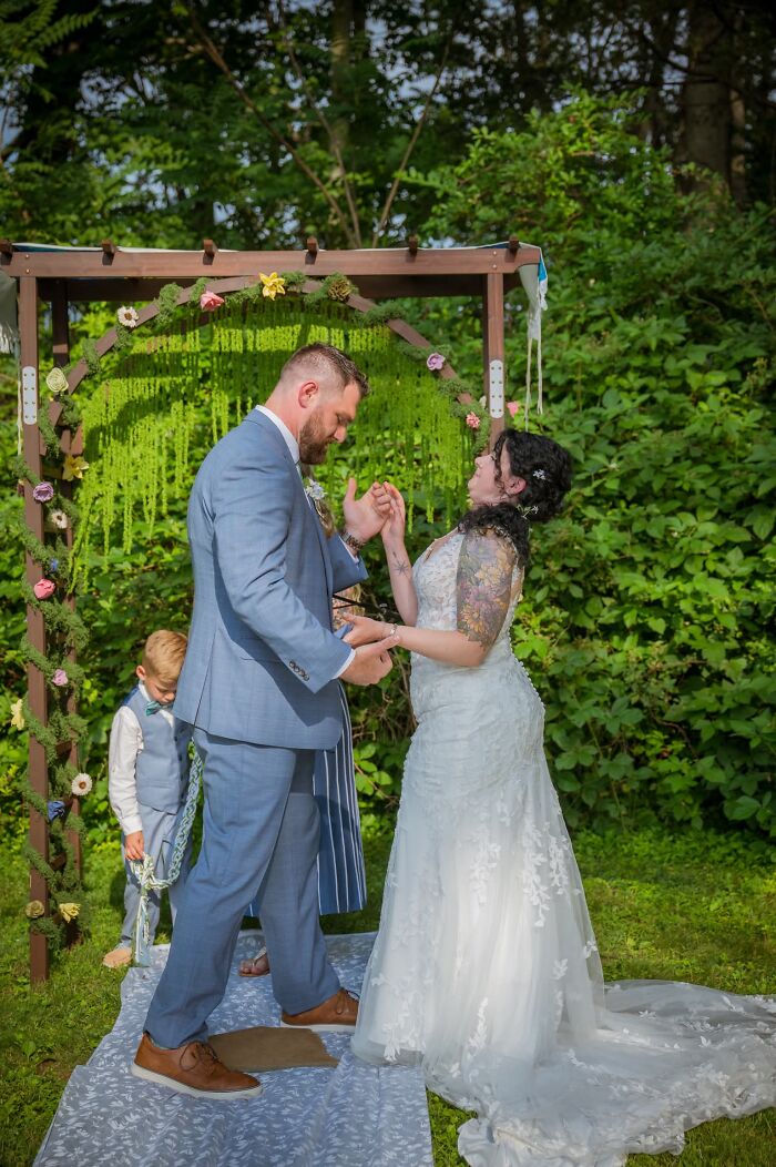 A happy bride and groom holding hands during an outdoor wedding ceremony, a funny wedding photo with a little boy.