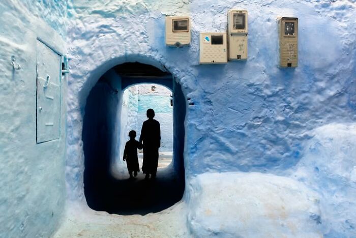 Murat Bakmaz captures the beauty of everyday life, depicting two figures walking through a blue archway.