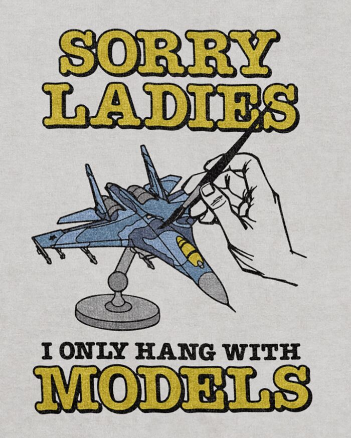 An iconic shirt with a graphic of a hand painting a model airplane and the text: SORRY LADIES I ONLY HANG WITH MODELS.