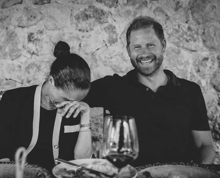 Meghan Markle and Prince Harry laughing together at a table, sparking outrage over their UK return. Meghan Markle and Prince Harry laughing together at a table, sparking outrage over their UK return.