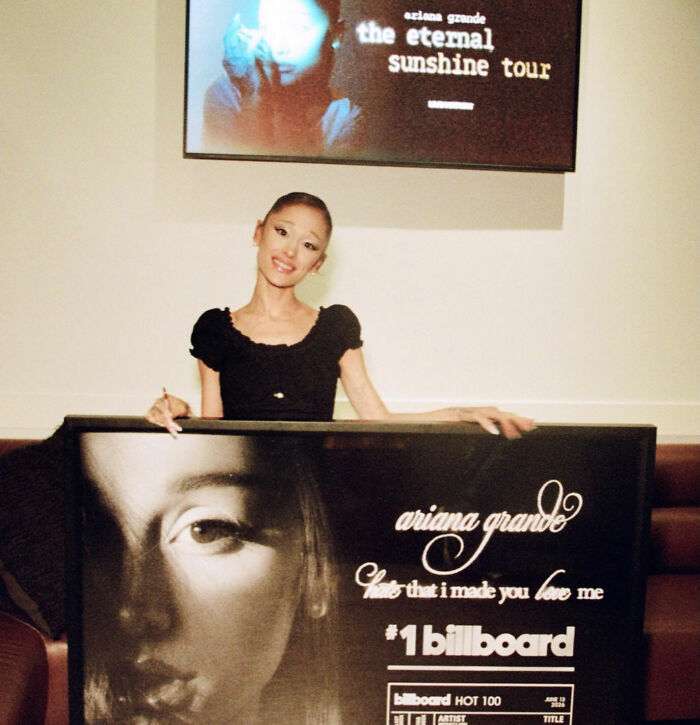 Ariana Grande smiling while holding a #1 Billboard award, stunning fans with her music video. Ariana Grande smiling while holding a #1 Billboard award, stunning fans with her music video.