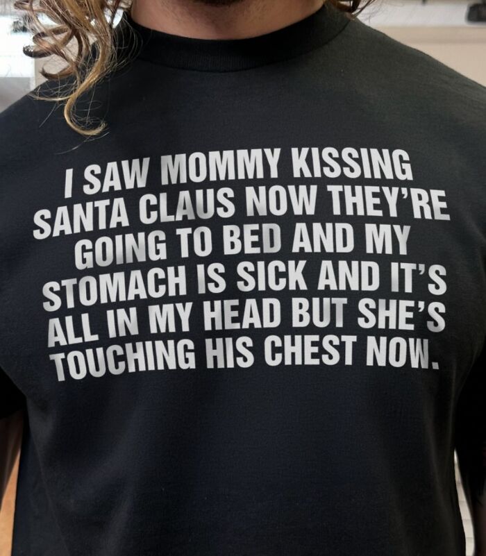 A person wearing an iconic shirt that reads: I SAW MOMMY KISSING SANTA CLAUS NOW THEY'RE GOING TO BED AND MY STOMACH IS SICK AND IT'S ALL IN MY HEAD BUT SHE'S TOUCHING HIS CHEST NOW.