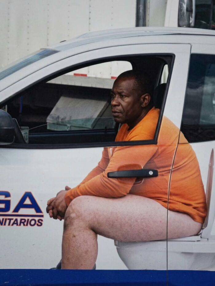 A man sitting on a toilet in the driver's seat of a truck, a funny moment captured by photographers.