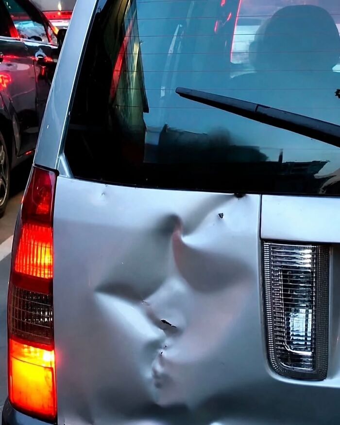 A photographer captures a funny moment of a car's dented bumper resembling a face puckering for a kiss.