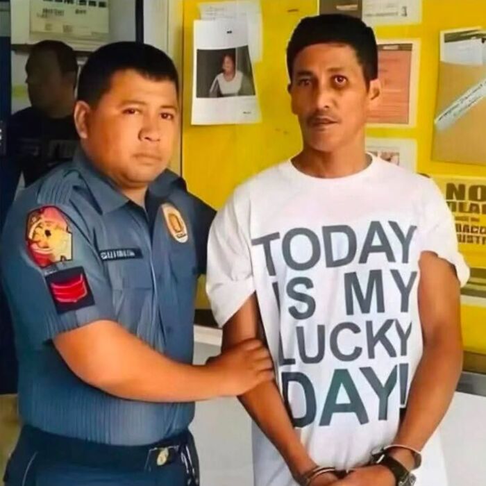 A photographer captures a man in handcuffs wearing a T-shirt that says TODAY IS MY LUCKY DAY!