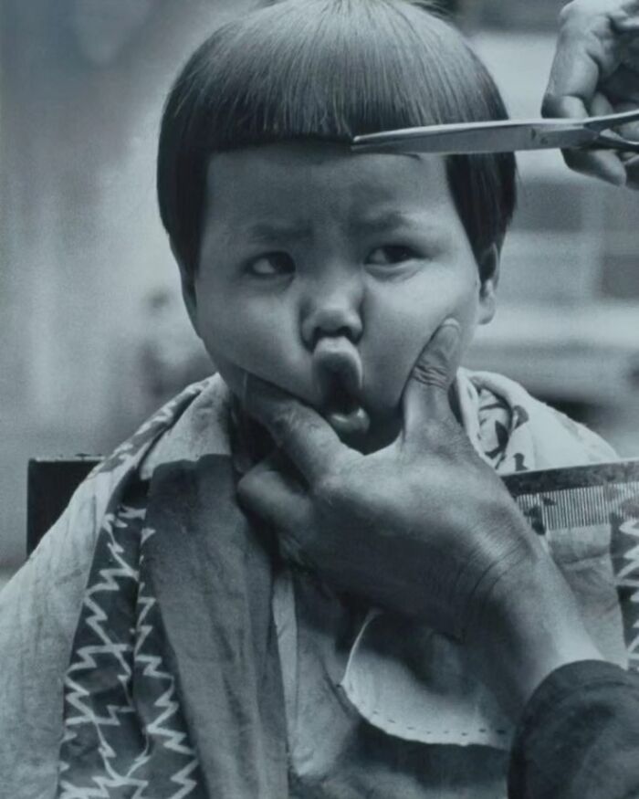 A photographer capturing a funny moment of a child making a face during a haircut.