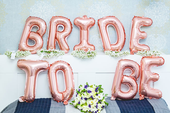 Rose gold balloons spelling BRIDE TO BE and a bouquet, decor for a wedding celebration.