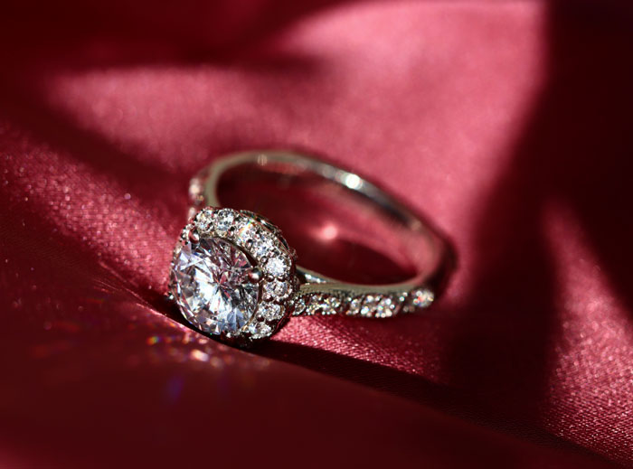 A sparkling diamond engagement ring on a red satin surface, symbolizing a commitment and whether someone is considered wife material.
