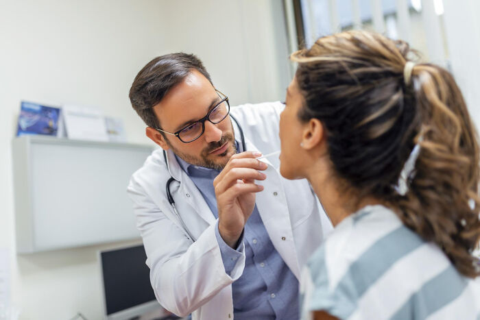 A male doctor examining a patient's throat, representing a common medical diagnosis procedure.