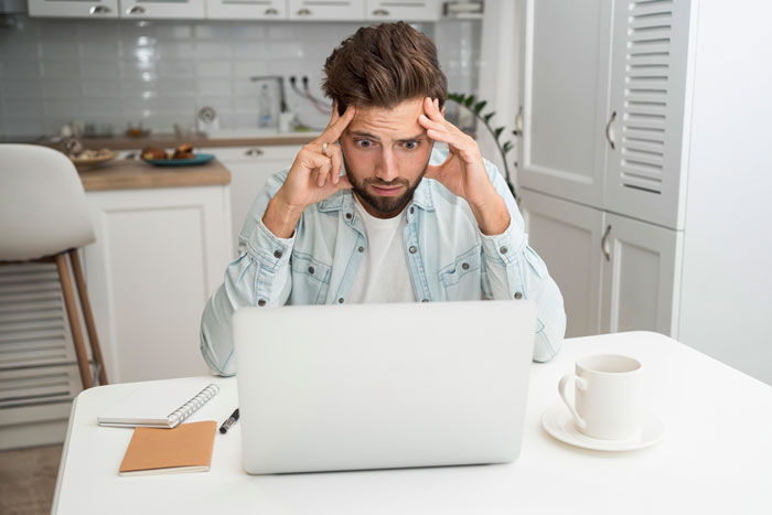 A man looking frustrated at a laptop, illustrating a victim of a workplace bully stealing credit for work. A man looking frustrated at a laptop, illustrating a victim of a workplace bully stealing credit for work.