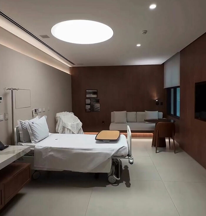 A luxurious maternity suite with a hospital bed, a couch, and modern lighting.