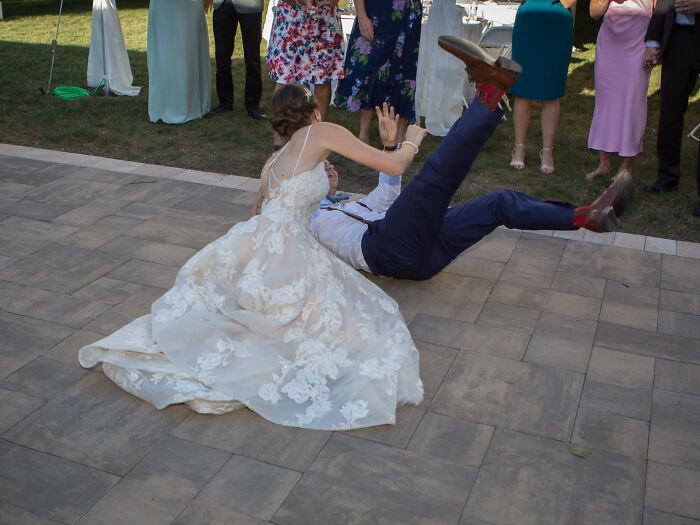 Bride and groom fall while dancing, creating a funny and iconic wedding photo moment.