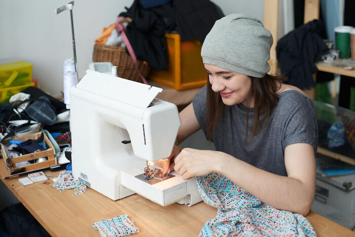 Woman learning to sew, picking up a new skill that could genuinely change her life.