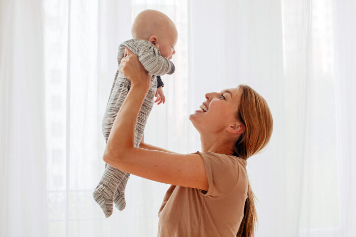A happy mother holds up her baby, a joyful moment contrasting the serious topic of hardest diagnoses.