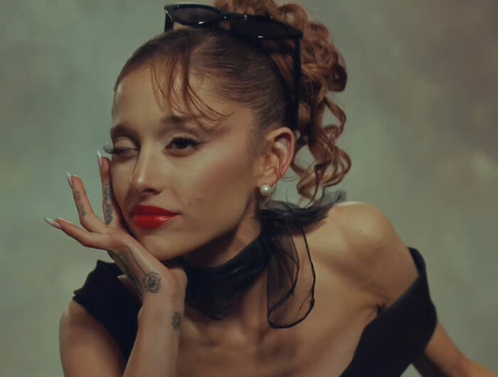 Ariana Grande with red lipstick and sunglasses on her head, winking. Her music video appearance stunned fans. Ariana Grande with red lipstick and sunglasses on her head, winking. Her music video appearance stunned fans.