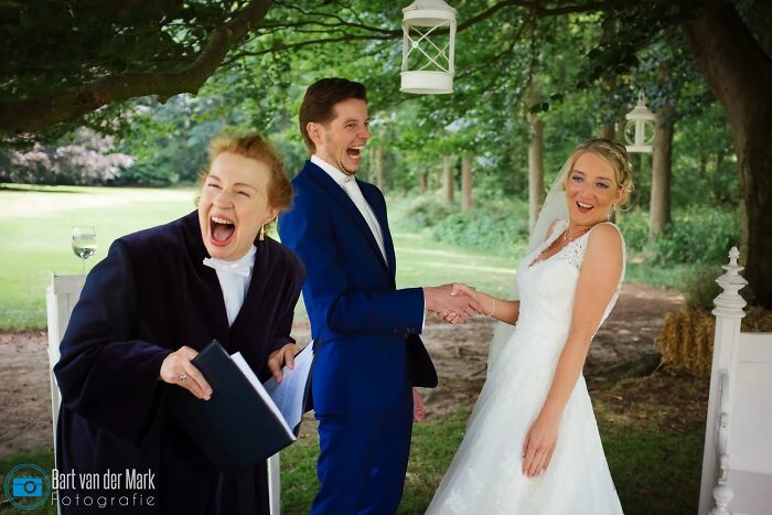Officiant and groom laugh heartily as the bride smiles, creating a funny wedding photo.