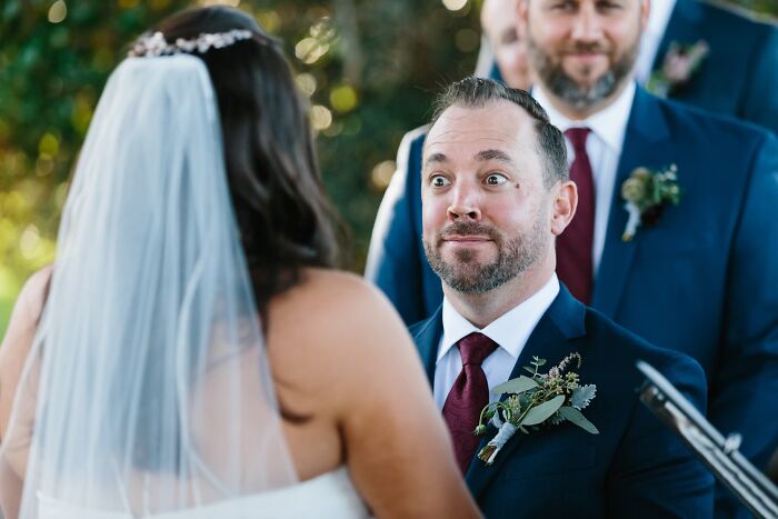 A groom making a funny wedding photo expression while looking at the bride during the ceremony.