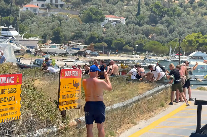 People standing near warning signs about danger from a plane's jet engine, risking severe injuries.