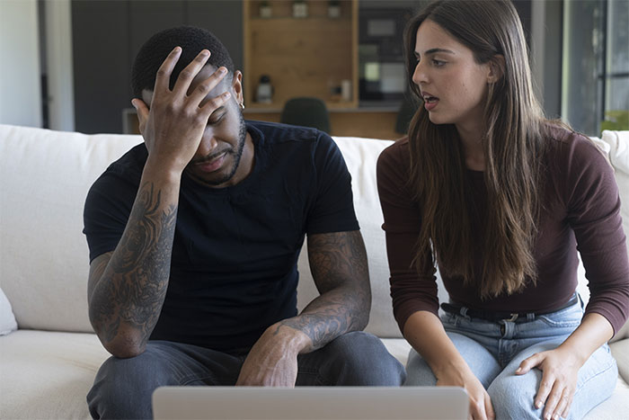 A man looking stressed while a woman talks, addressing boundaries in a shared house.