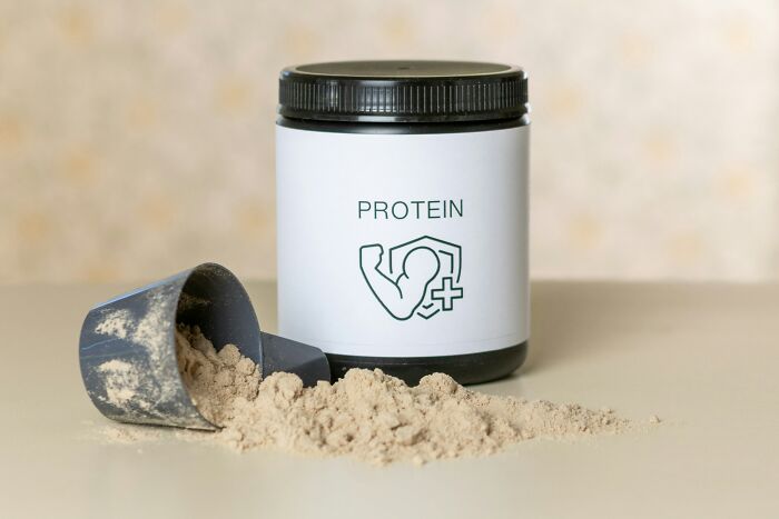 A tub of protein powder with a scoop beside it, representing healthy habits that might be glorified.