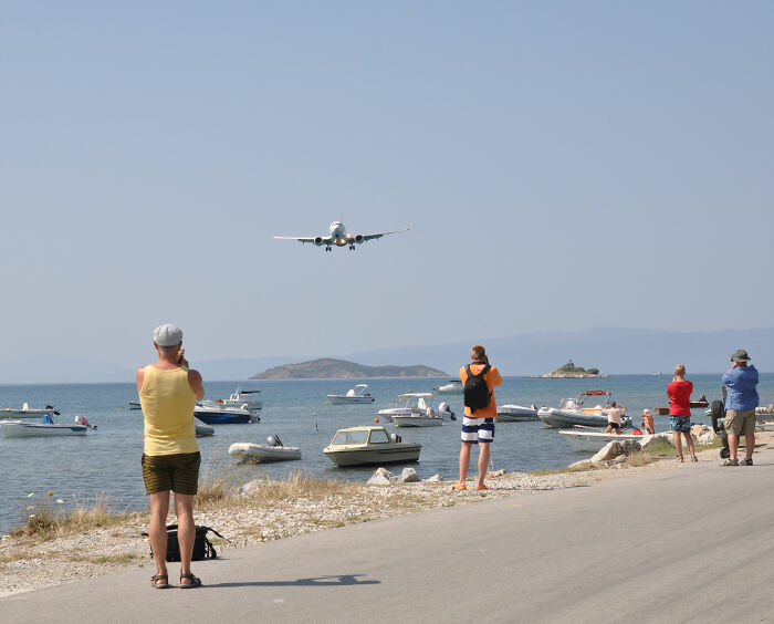 Woman injured by a plane's jet engine near a plane landing over water, with boats and onlookers.