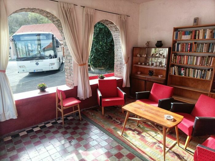 A waiting room with red chairs and a bookshelf, looking out at a Volanbus bus, showing why Eastern Europe is built different.