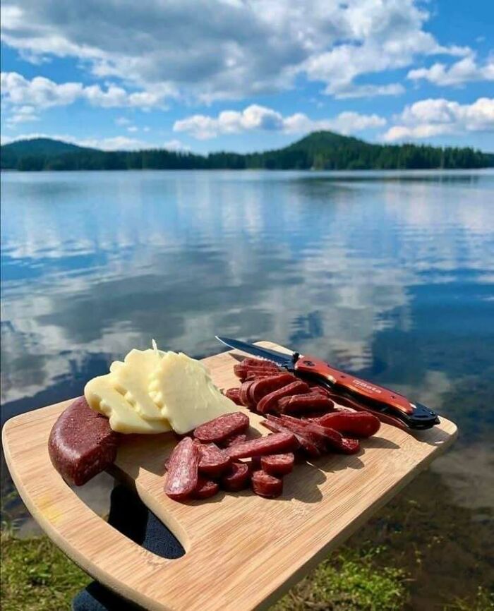 A scenic view of a lake with a wooden board of cheese and sausage, showing why Eastern Europe is built different.