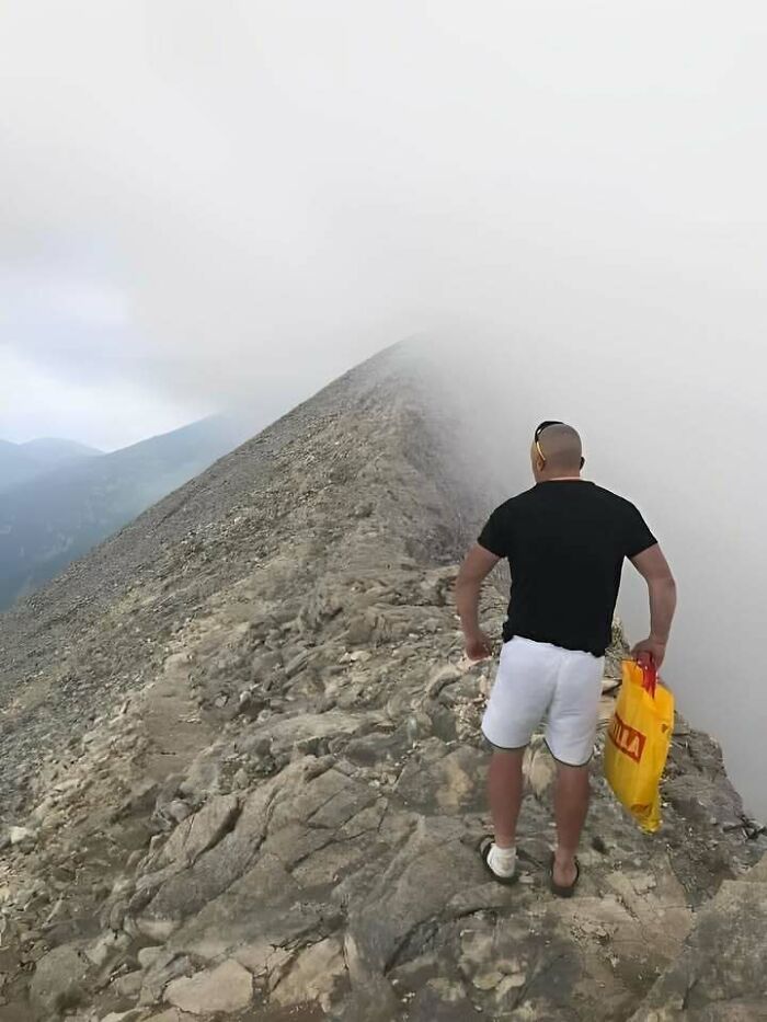 A man with a shopping bag on a foggy mountain ridge, illustrating how people from Eastern Europe are built different.