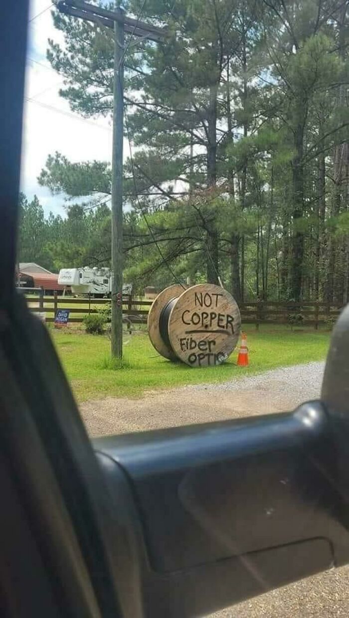 A large wooden spool in Eastern Europe with a sign that says NOT COPPER Fiber Optic, indicating local resourcefulness.