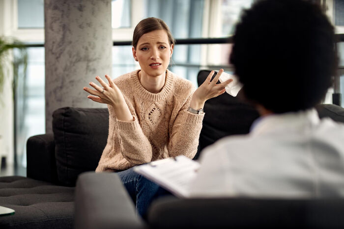 A woman talking with her hands to a therapist during a therapy session. She walked into therapy and walked out without her therapist.