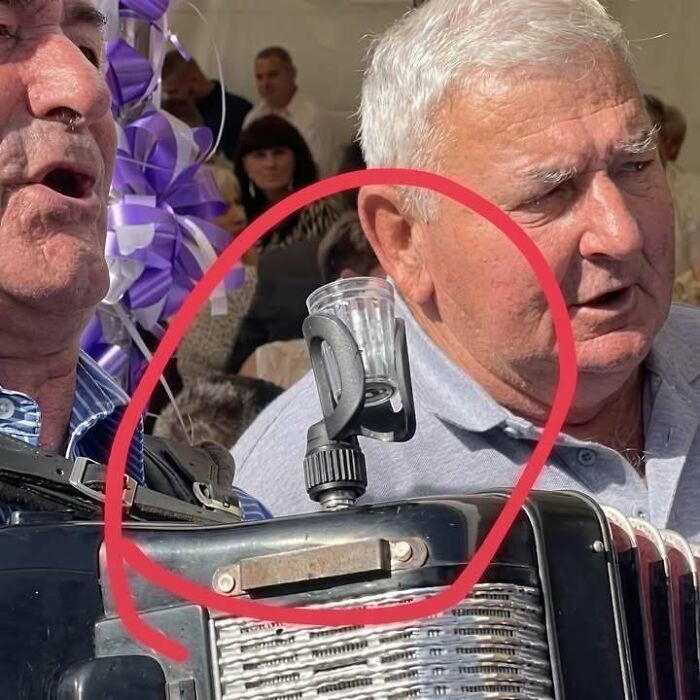 Eastern European man with a shot glass holder attached to his accordion, showing people are built different.