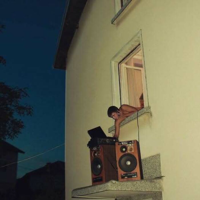 A person reaching out a window to adjust speakers and a laptop, an example of Eastern Europe being built different.