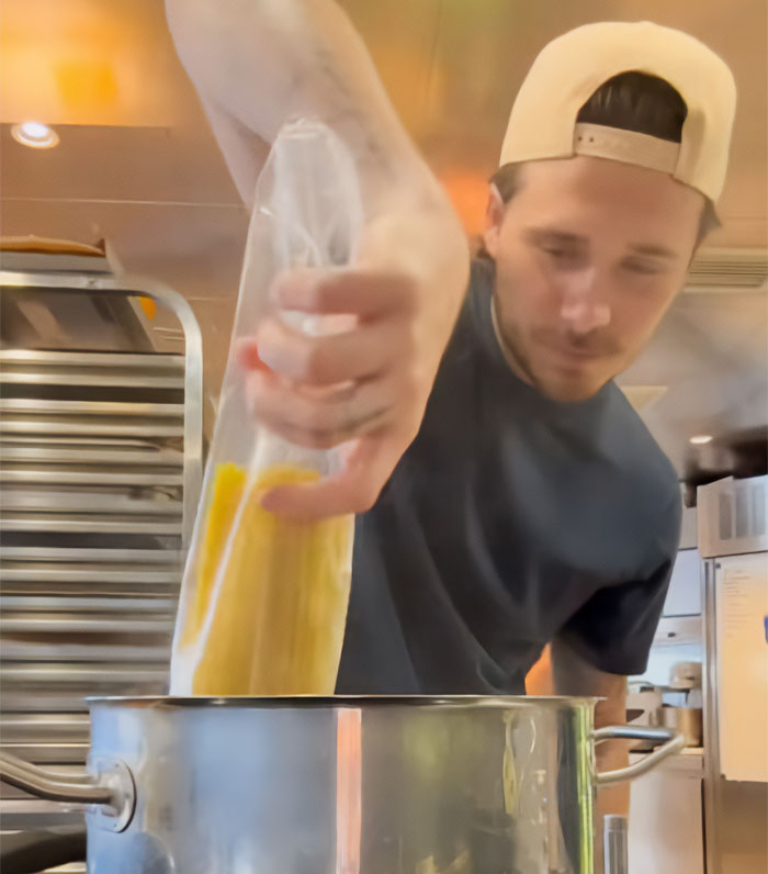 Brooklyn Beckham pouring pasta from a plastic bag into a cooking pot on a boat for his latest cooking video.