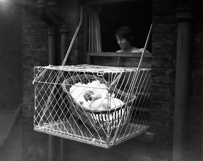 A baby in a wire cage hanging out of a window, representing a parent's wrong way to solve a problem.