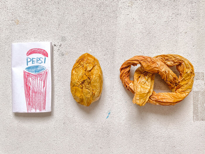 Surreal paper creations: a crumpled paper potato and pretzel next to a hand-drawn Pepsi can, exploring paper sculpture.