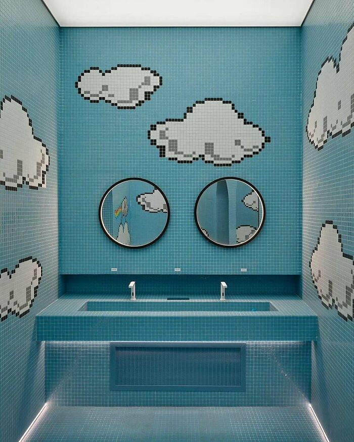 Brilliant designs of a bathroom with pixelated clouds on blue tiles, dual sinks, and round mirrors highlighting career.
