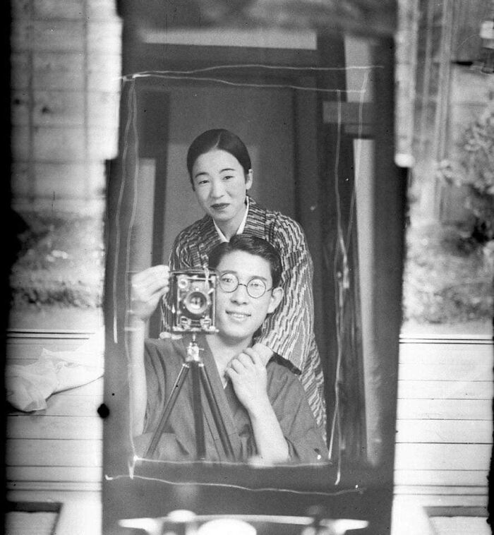 A black and white photo of a Japanese couple taking a mirror selfie, capturing a moment nearly lost to history.
