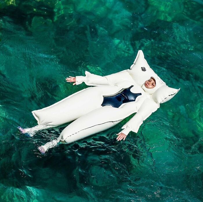 A person in a white inflatable suit floating on brilliant and beautiful turquoise water, showcasing clever designs.