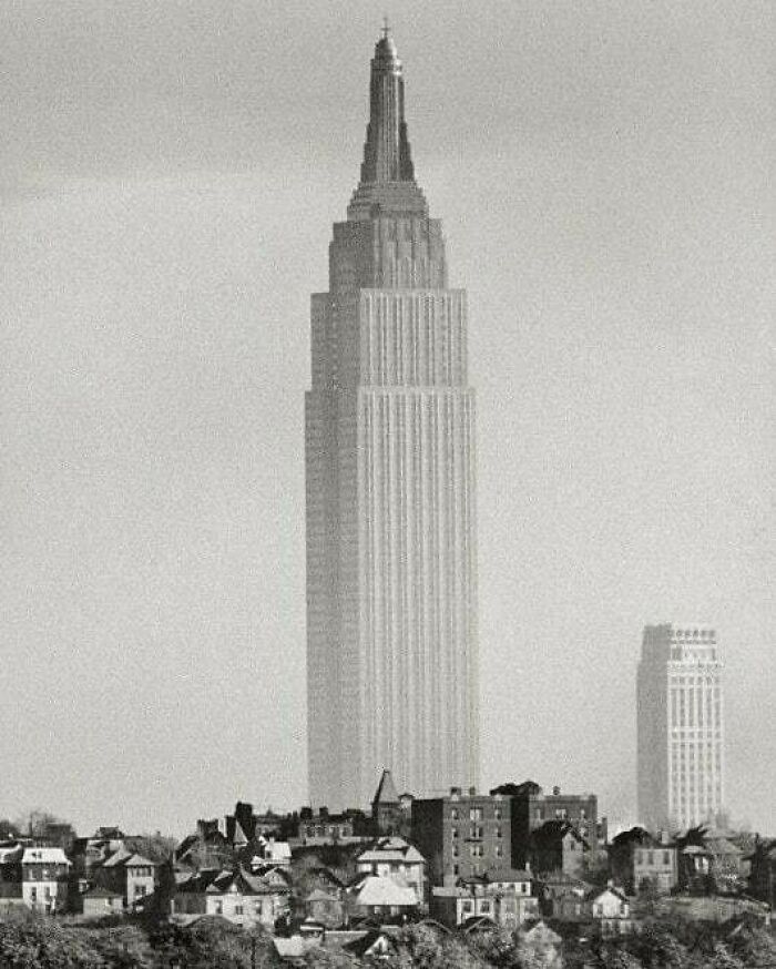 The Empire State Building towering over smaller structures in a black and white photo, a moment nearly lost to history.